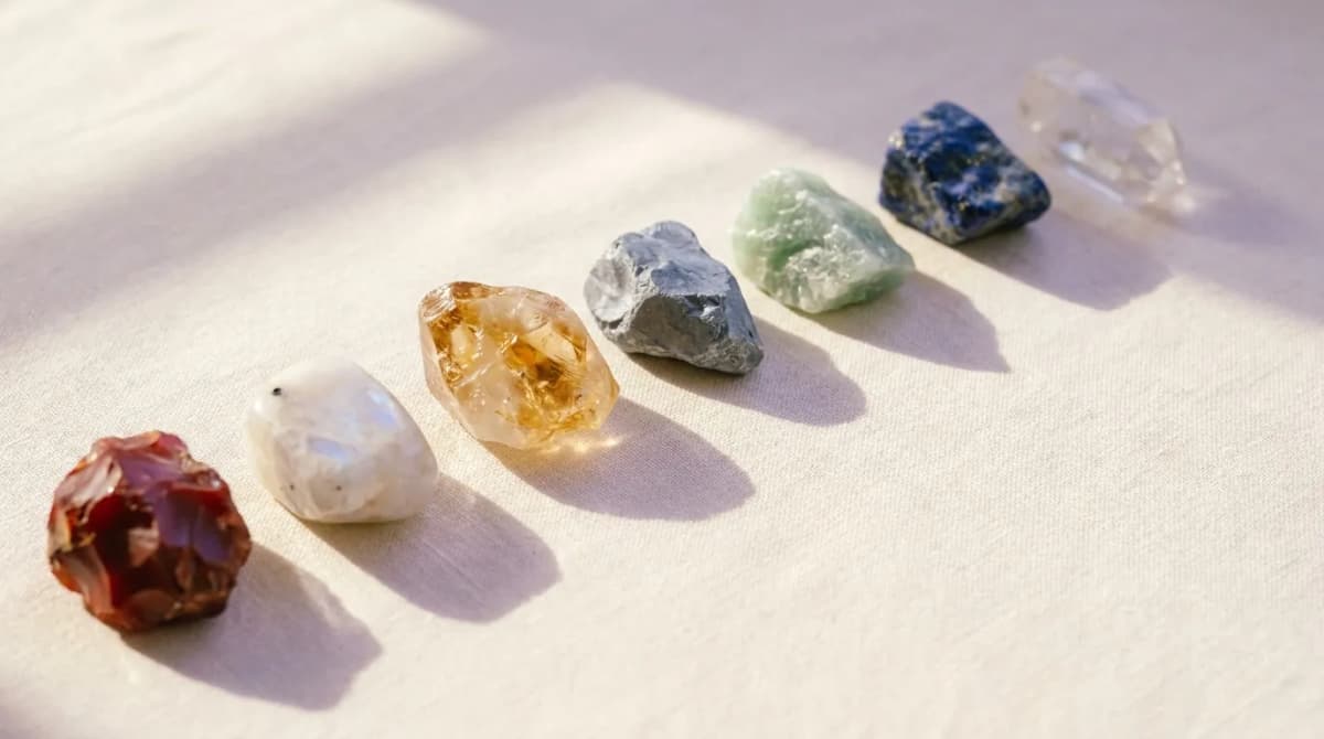 Seven rough minerals laid out in a row on linen cloth